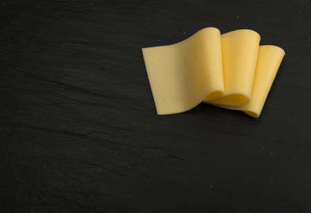 Sliced Cheese Over Black Stone Background with Space for Text Top Viewの写真素材