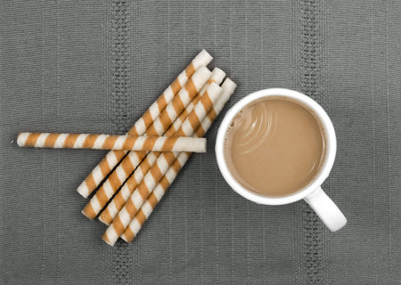 Chocolate Wafer Sticks and Cup of Coffee with Milk on Gray Background