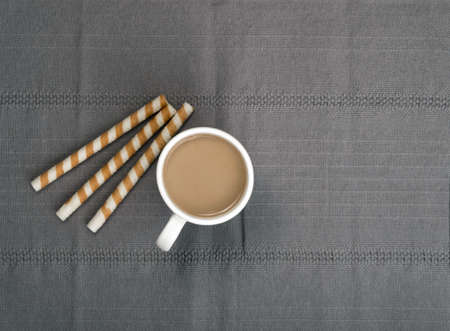 Chocolate Wafer Sticks and Cup of Coffee with Milk on Gray Backgroundの写真素材