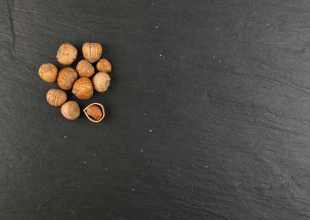 Heap of Hazelnuts in Shell on Black Stone Background with Place for Textの写真素材