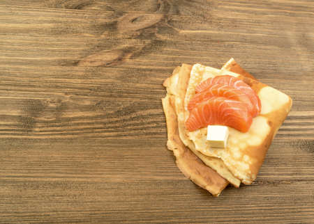 Crepes with Raw Sliced Salmon Fillet. Thick Pieces of Red Trout with Pancakes on Dark Wooden Backgroundの写真素材