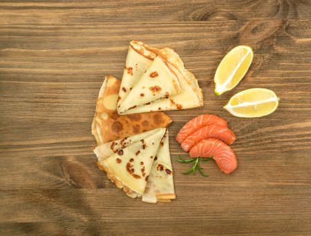 Crepes with Raw Sliced Salmon Fillet. Thick Pieces of Red Trout with Pancakes on Dark Wooden Backgroundの写真素材