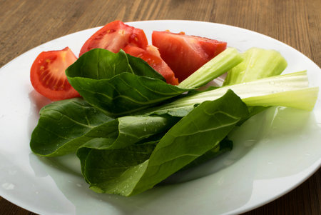 Sliced Tomatoes with Fresh Green Salad on White Plate. Chinese cabbage or Bok choyの写真素材