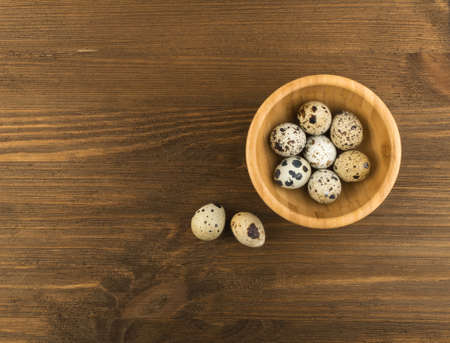 Quail Eggs on Wooden Rustic Background Top View. Small Whole Eggs with Place for Textの写真素材