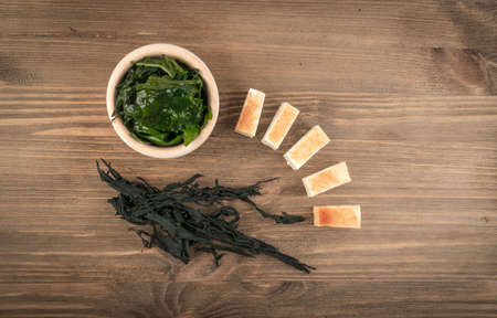 Dry Wakame Seaweed on Natural Wooden Background. Healthy Algae Food with Soy Sauce and Tofu Top Viewの写真素材