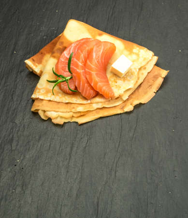 Crepes with Raw Sliced Salmon Fillet. Thick Pieces of Red Trout with Pancakes on Black Stone Backgroundの写真素材