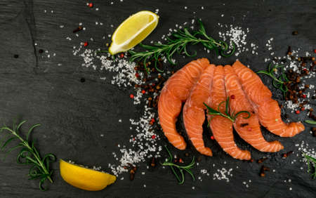 Raw Sliced Salmon Fillet on Black Stone Background. Thick Pieces of Fresh Trout. Red Fish Sashimiの写真素材