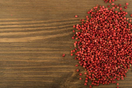 Pink Pepper or Red Pepper Corns on Wooden Background. Schinus Dry Seeds on Wood Rustic Tabletopの写真素材