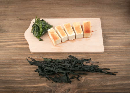 Dry Wakame Seaweed on Natural Wooden Background. Healthy Algae Food with Soy Sauce and Tofuの写真素材