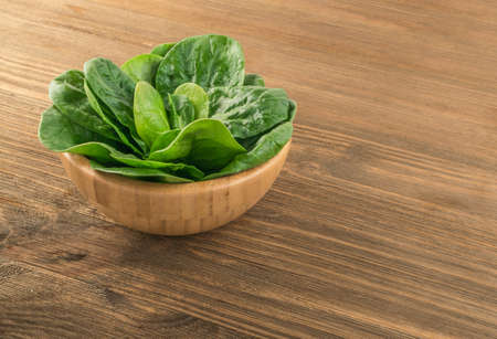 Fresh Baby Spinach Leaves. Spinacia Oleracea on Wooden Background. Leafy Green Vegetableの写真素材