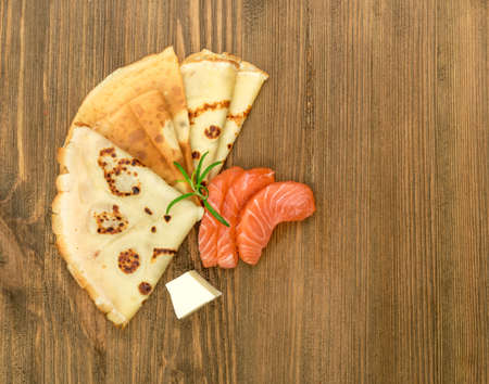 Crepes with Raw Sliced Salmon Fillet. Thick Pieces of Red Trout with Pancakes on Dark Wooden Backgroundの写真素材