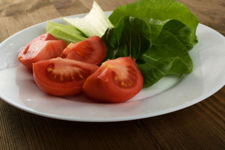 Sliced Tomatoes with Fresh Green Salad on White Plateの写真素材