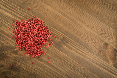 Pink Pepper or Red Pepper Corns on Wooden Background. Schinus Dry Seeds on Wood Rustic Tabletopの写真素材