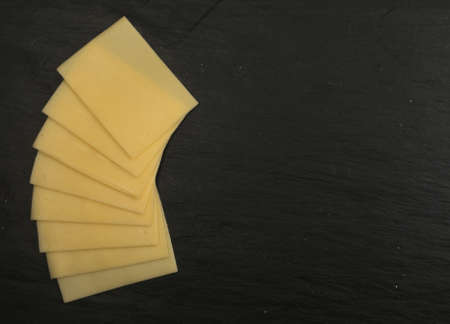 Sliced Cheese Over Black Stone Background with Space for Text Top Viewの写真素材