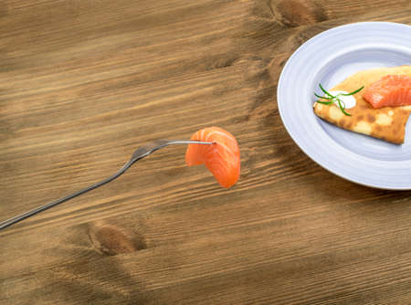 Salmon Fillet on Fork. Thick Piece of Red Trout with Pancakes on Blue Plateの写真素材