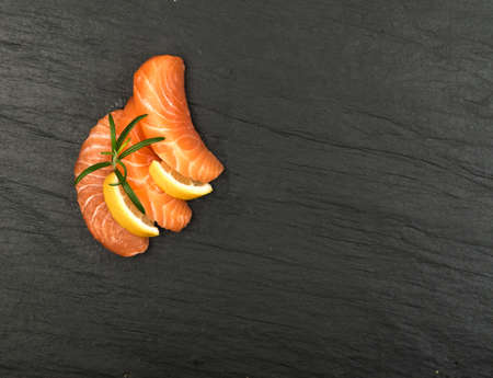 Raw Sliced Salmon Fillet on Black Stone Background. Thick Pieces of Fresh Trout. Red Fish Sashimiの写真素材