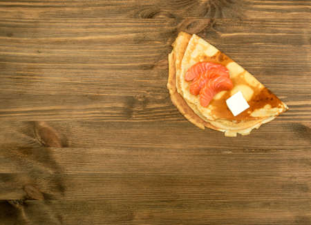 Crepes with Raw Sliced Salmon Fillet. Thick Pieces of Red Trout with Pancakes on Dark Wooden Backgroundの写真素材