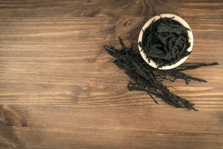 Heap of Dry Wakame Seaweed on Wooden Background. Healthy Algae Food with Place for Textの写真素材