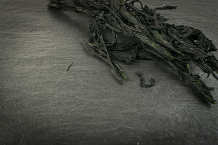 Heap of Dry Wakame Seaweed on Black Stone Background. Healthy Algae Food with Place for Textの写真素材