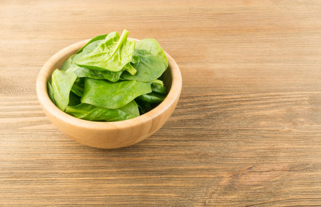 Heap of Fresh Green Baby Spinach or Spinacia Oleracea Leaves. Leafy Green Vegetable on Rustic Wooden Background with Place for Textの写真素材