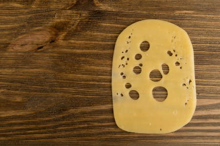 Thin Slices of Swiss Cheese on Wooden Background Top View and Flat Lay. Natural Rustic Backdrop with Place for Textの写真素材