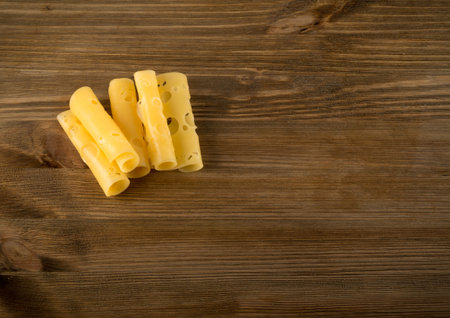 Thin Slices of Swiss Cheese on Wooden Background Top View and Flat Lay. Natural Rustic Backdrop with...