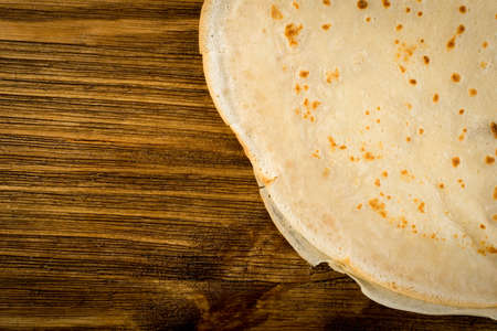 Thin Pancakes on Natural Wooden Rustic Background Top View. Fresh Homemade Crepes Flat Lay with Space for Textの写真素材