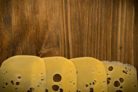 Thin Slices of Swiss Cheese on Wooden Background Top View and Flat Lay. Natural Rustic Backdrop with Place for Textの写真素材