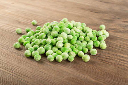 Heap of Frozen Sweet Green Peas on Wooden Backgroundの写真素材