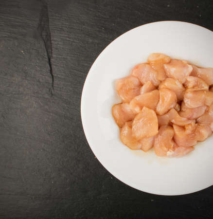 Raw Chicken Breast with Soy Souse in White Bowl on Black Background. Fresh Turkey Fillet Chunks Top Viewの写真素材