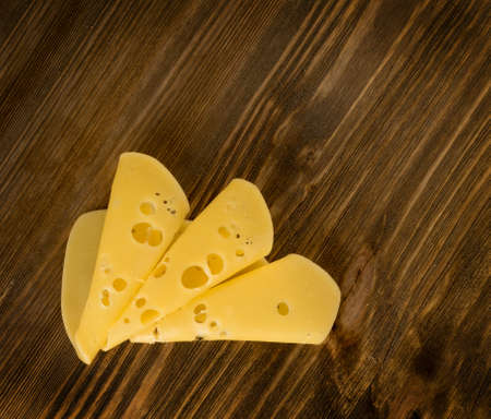 Thin Slices of Swiss Cheese on Wooden Background Top View and Flat Lay. Natural Rustic Backdrop with Place for Textの写真素材