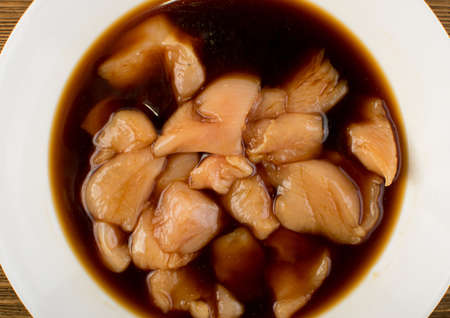 Raw Chicken Breast Marinated in Soy Souse. Fresh Turkey Fillet Chunks on Wooden Background Top Viewの写真素材