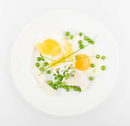 Fried Eggs with Green Peas, Onion and Tofu Cheese on White Plateの写真素材