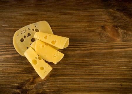 Thin Slices of Swiss Cheese on Wooden Background Top View and Flat Lay. Natural Rustic Backdrop with Place for Textの写真素材