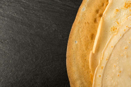 Thin Pancakes on Black Stone Background Top View. Fresh Homemade Crepes or Flatbread Flat Lay with Space for Textの写真素材