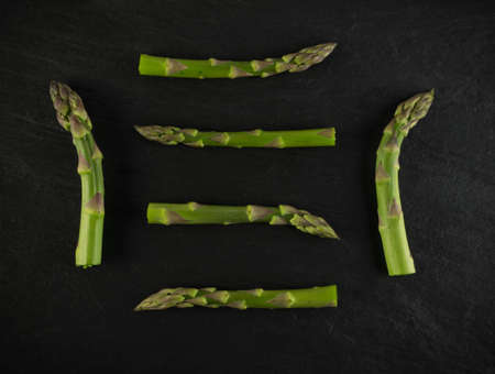 Bunch of Raw Garden Asparagus Top View. Fresh Green Spring Vegetables on Black Stone Background.の写真素材