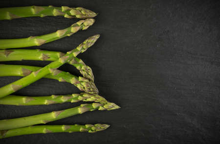 Bunch of Raw Garden Asparagus Top View. Fresh Green Spring Vegetables on Natural Stone Background with Space for Text.の写真素材