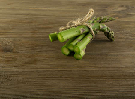 Bunch of Raw Garden Asparagus. Fresh Green Spring Vegetables on Wooden Background with Space for Text.の写真素材