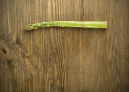 One Stem of Raw Garden Asparagus Top View. Fresh Green Spring Vegetable on Wooden Background with Space for Text.の写真素材