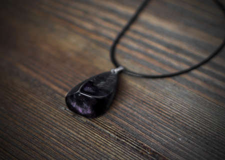 Pendant of Dark Color on Wooden Background. Bijouterie Made of Epoxy Resinの写真素材