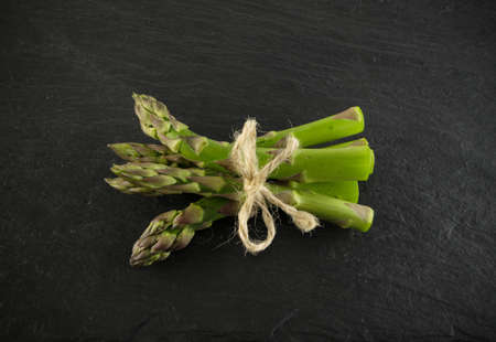 Bunch of Raw Garden Asparagus Top View. Fresh Green Spring Vegetables on Black Stone Background.の写真素材