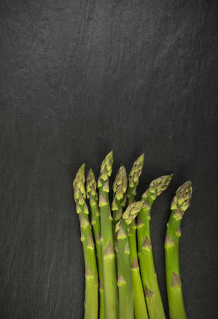 Bunch of Raw Garden Asparagus Top View. Fresh Green Spring Vegetables on Natural Stone Background with Space for Text.の写真素材