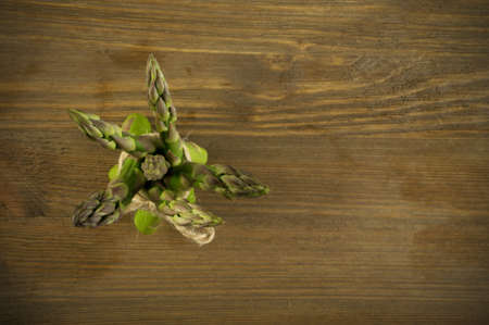 Bunch of Raw Garden Asparagus Top View. Fresh Green Spring Vegetables on Wooden Background with Space for Text.の写真素材