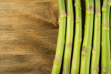 Raw Garden Asparagus Stems Top View. Fresh Green Spring Vegetables on Wooden Background with Space for Text.の写真素材