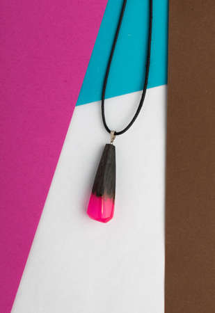 Hand Made Scarlet Wood Pendant on Abstract Multicolored Geometric Background. Bijouterie Made of Epoxy Resin and Woodの写真素材