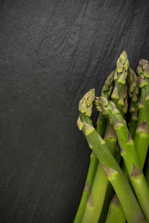 Bunch of Raw Garden Asparagus Top View. Fresh Green Spring Vegetables on Natural Stone Background with Space for Text.の写真素材