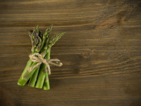Bunch of Raw Garden Asparagus Top View. Fresh Green Spring Vegetables on Wooden Background with...
