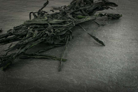 Heap of Dry Wakame Seaweed on Black Stone Background. Healthy Algae Food with Place for Textの写真素材