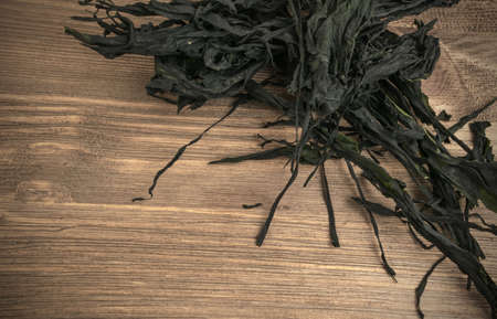 Heap of Dry Wakame Seaweed on Wooden Background. Healthy Algae Food with Place for Textの写真素材