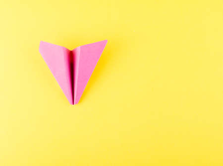 Pink Paper Plane or Paper Airplane Origami on Yellow Background Top View with Place for Textの写真素材